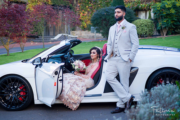 Bride & Groom posing by a sports car on their wedding day