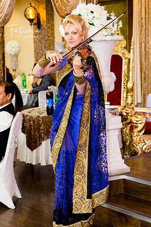 A white girl wearing a sari while playing violin
