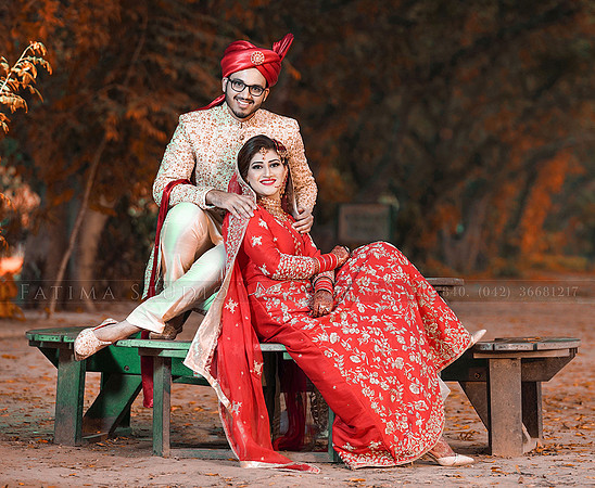 Pakistani couple on a park bench on their wedding day